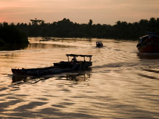 Mekong Smile Bassac Cruise Can Tho small boat cruising on Mekong River at sunset