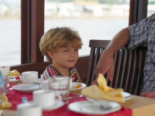 Child sitting at dinner table on Bassac Cruise in Can Tho, Mekong Delta