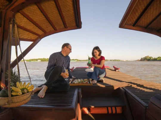 Couple enjoying sunset views on Bassac Cruise along the Hau River, Can Tho