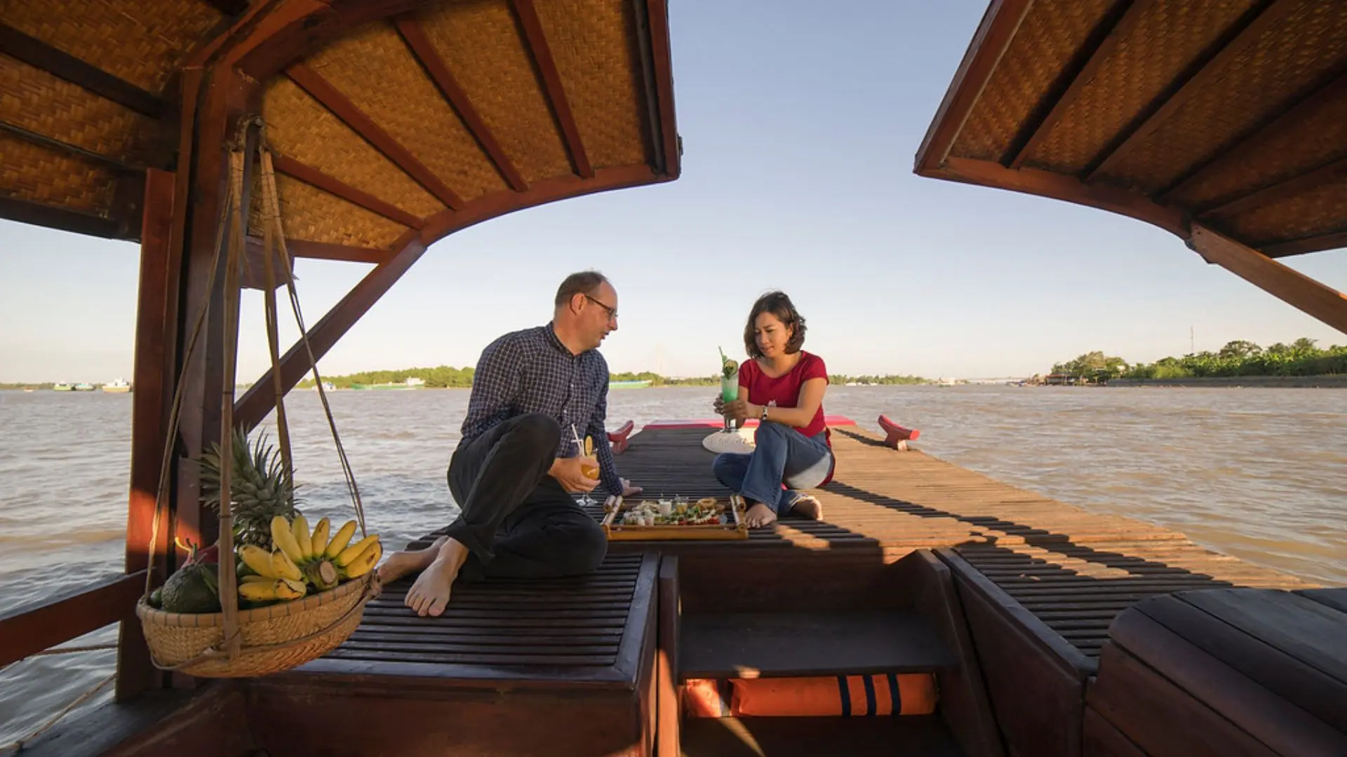 Couple enjoying sunset views on Bassac Cruise along the Hau River, Can Tho