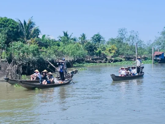 Tourists on wooden rowing boats navigating the river in Cai Be