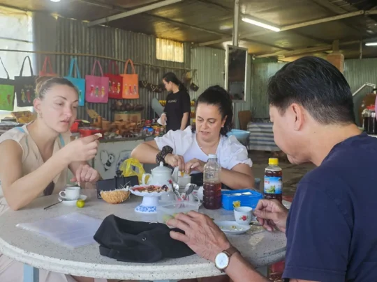 Tourists sitting at a table tasting local tea in a Cai Be workshop