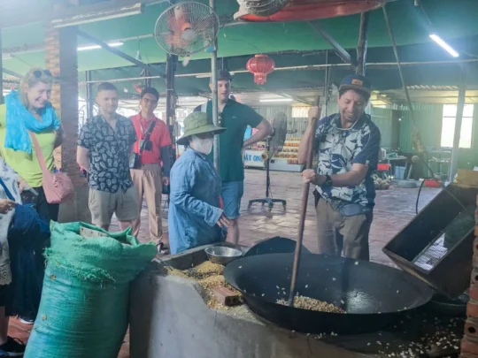 Tourists watching a local person cook in a traditional kitchen in Cai Be
