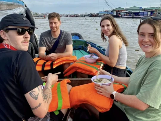 Local vendors interacting with tourists on boats at Cai Rang Floating Market, Can Tho