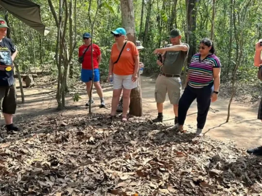 Tourist pointing at the tiny, concealed entrance to the Cu Chi Tunnels