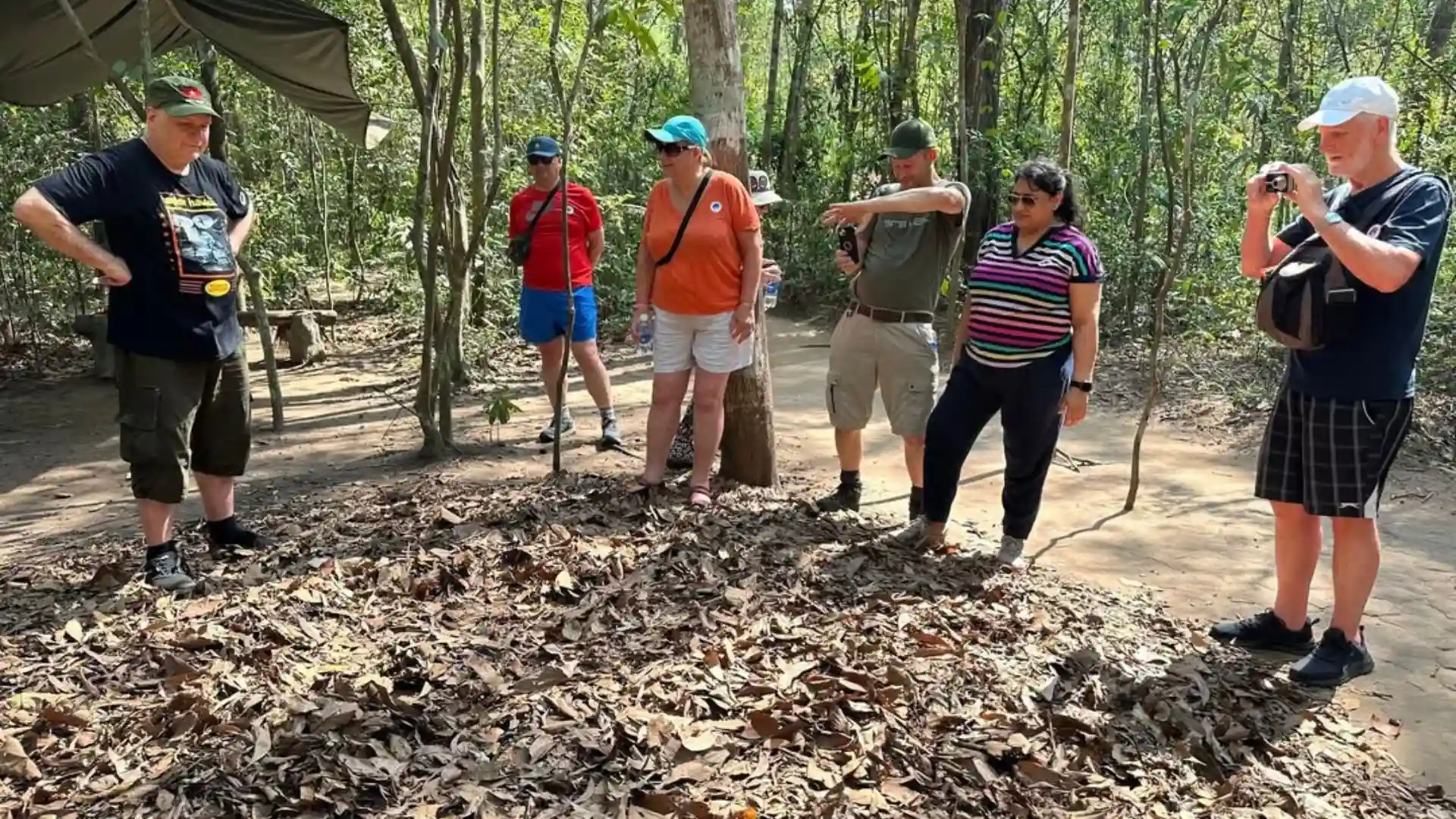Tourist pointing at the tiny, concealed entrance to the Cu Chi Tunnels