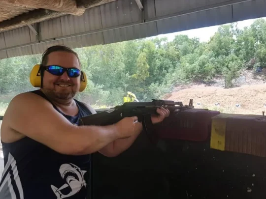 Tourist wearing ear protection and aiming a rifle at the shooting range in Cu Chi Tunnels Tour