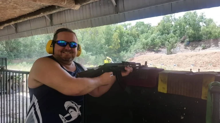Tourist wearing ear protection and aiming a rifle at the shooting range in Cu Chi Tunnels Tour