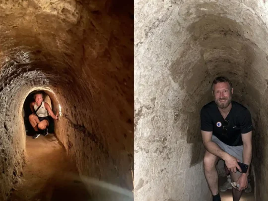 Tourists walking bent over due to the low ceiling in Cu Chi Tunnels Tour