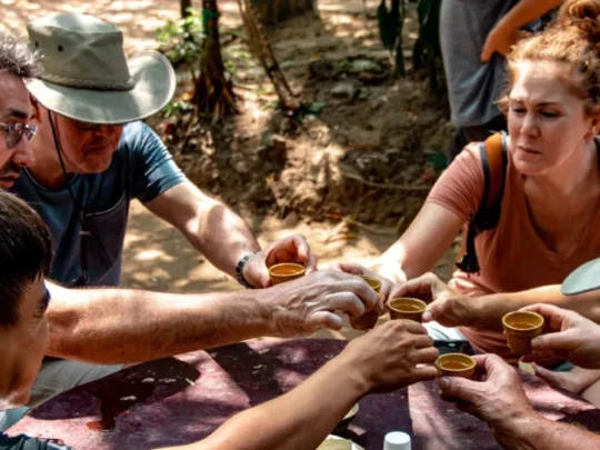 Tourists tasting boiled cassava/tapioca and tea in a shaded seating area in Cu Chi Tunnels Tour