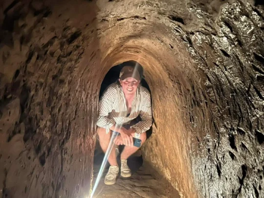 Tourists walking/crawling through a widened section of the Cu Chi Tunnel.
