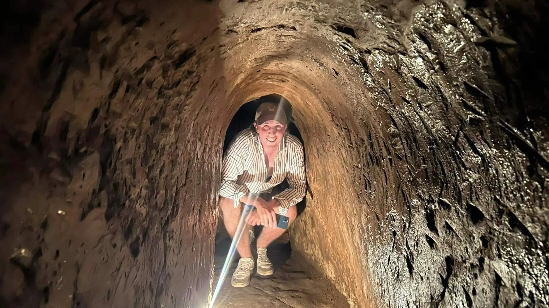 Tourists walking/crawling through a widened section of the Cu Chi Tunnel.