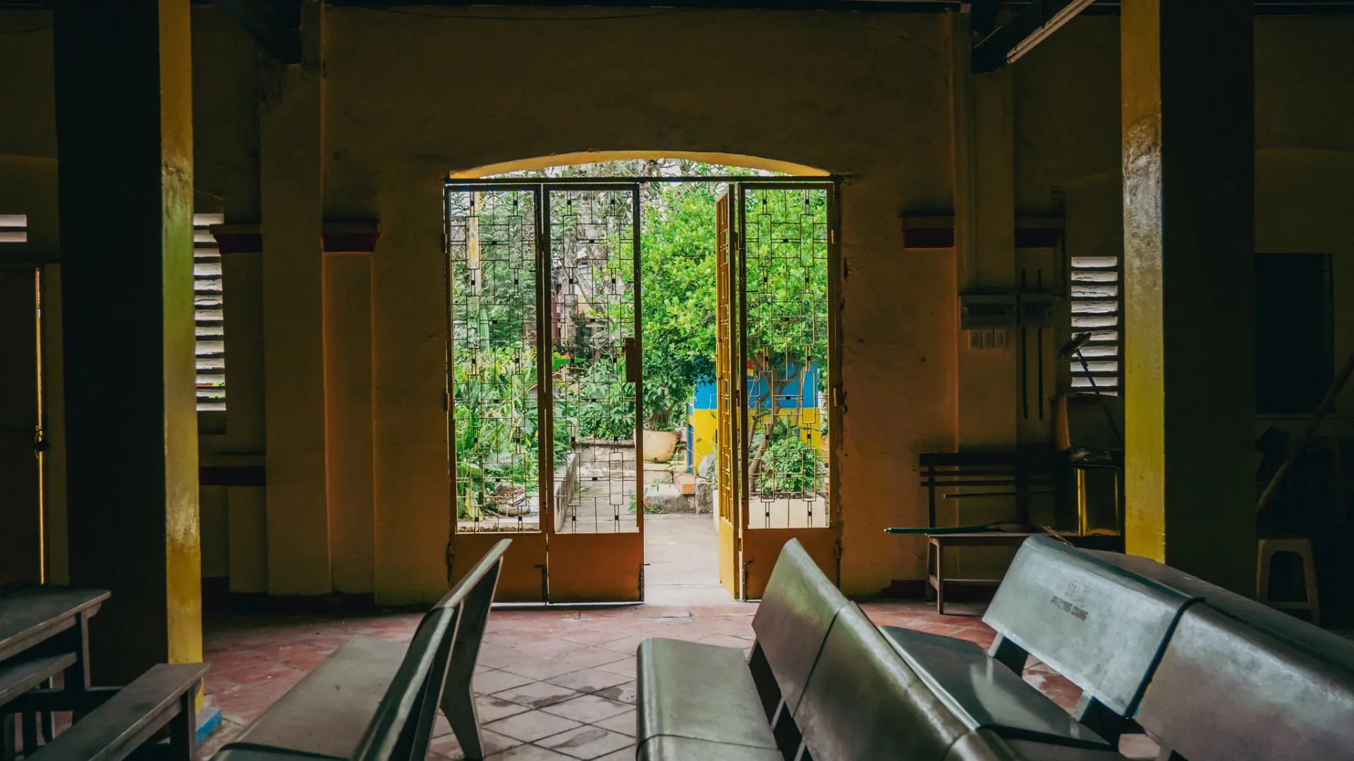Interior view of wooden pews and an open door at Dieu Hoa Temple