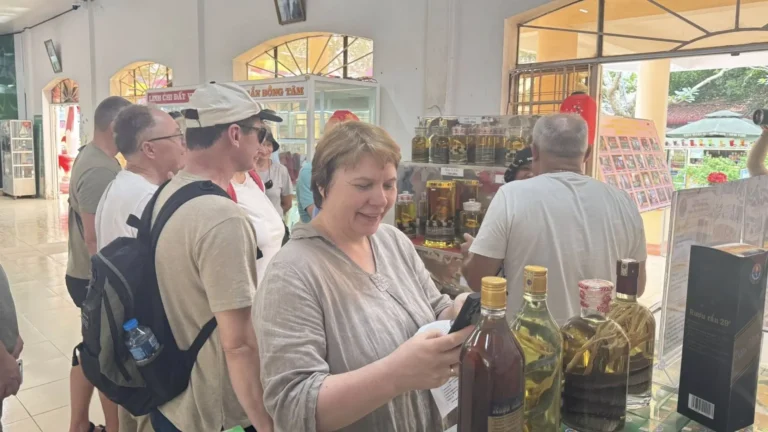 Tourists shopping for herbal wine and specialty products at Dong Tam Snake Farm souvenir shop in Tien Giang