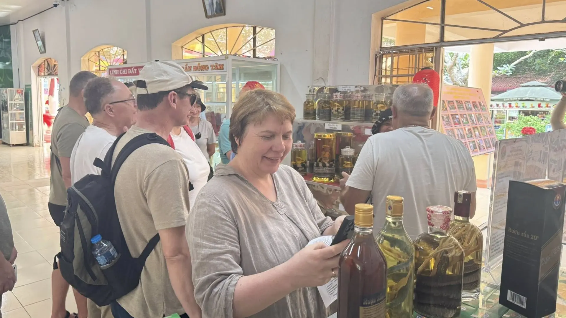 Tourists shopping for herbal wine and specialty products at Dong Tam Snake Farm souvenir shop in Tien Giang