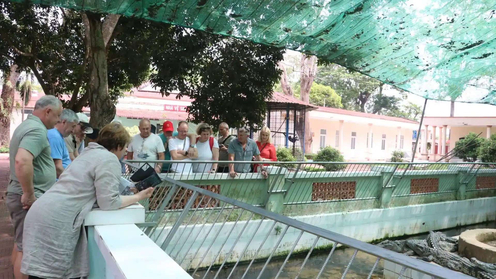 International visitors observing snake enclosures at Dong Tam Snake Farm, a famous wildlife attraction in Tien Giang, Vietnam