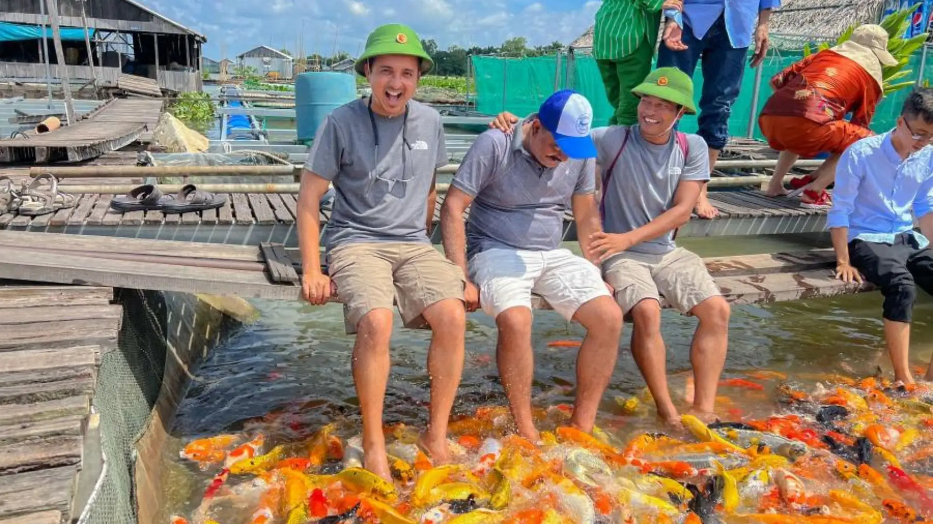 Guests feeding fish at Can Tho floating fish farm