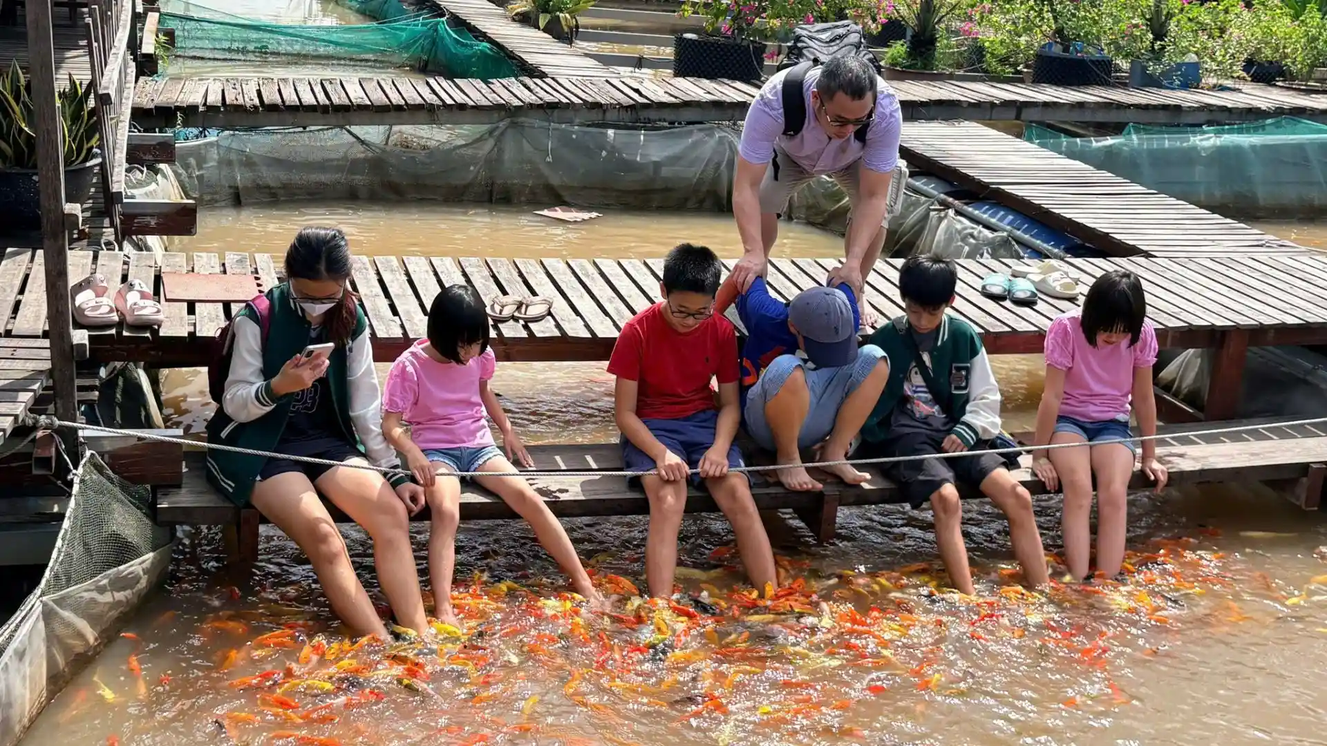 Children joining a fish-feeding activity at a floating fish farm