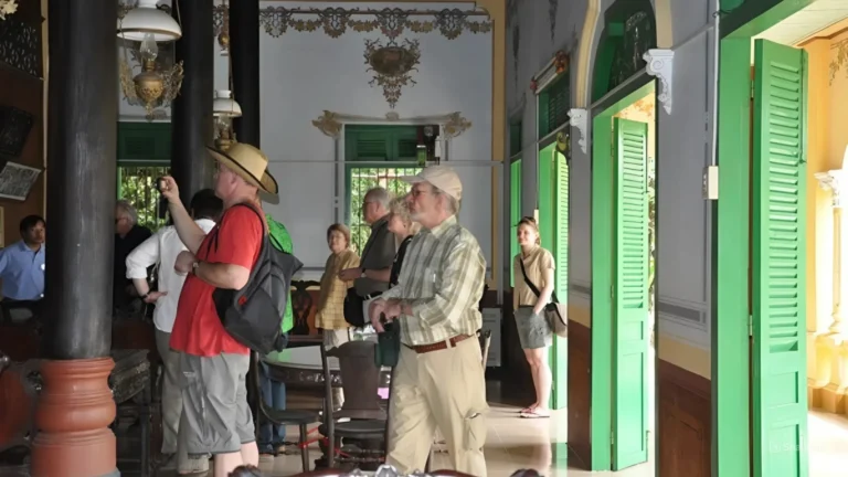 A tour guide explaining the history of Ba Duc Ancient House to visitors inside the main hall