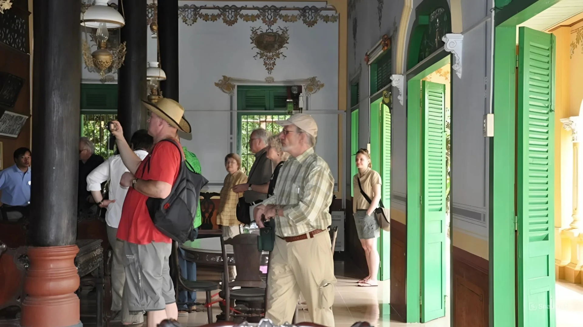A tour guide explaining the history of Ba Duc Ancient House to visitors inside the main hall