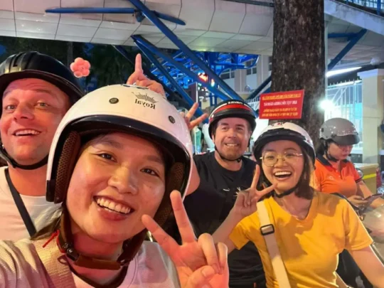 Tourists riding motorbikes at night during Ho Chi Minh City motorbike tour