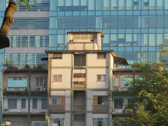 Old apartment building contrasted with modern architecture in Ho Chi Minh City