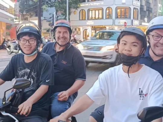 Group of travelers enjoying a Ho Chi Minh motorbike tour through busy city streets