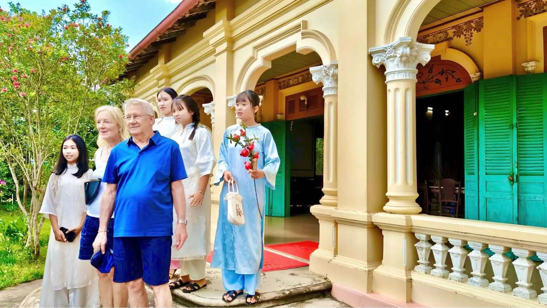 A group of international tourists being welcomed at the porch of Ba Duc Ancient House