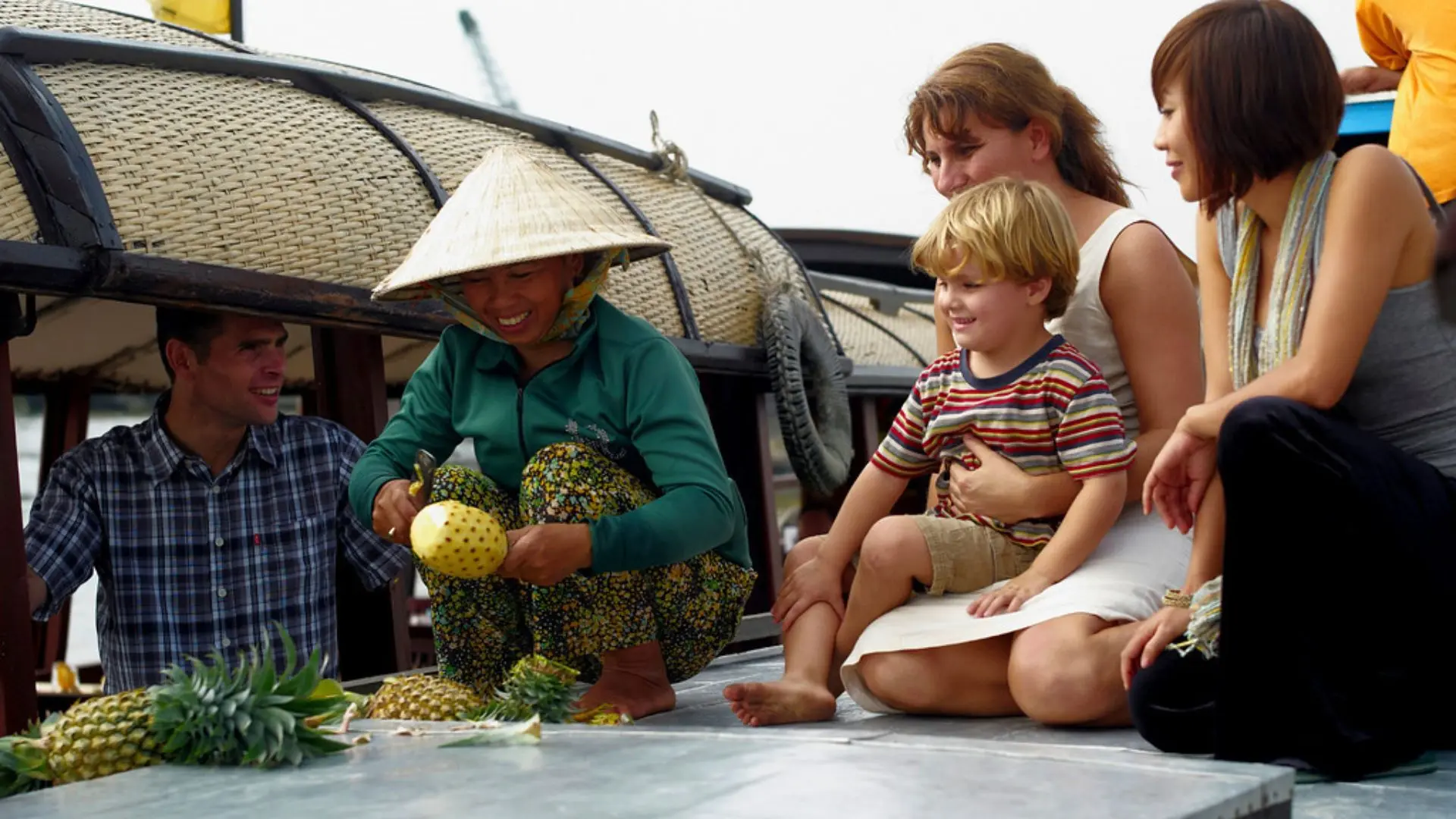 Guests experiencing cultural interaction with local vendors at Cai Rang Floating Market during a Mekong Delta cruise in Can Tho, Vietnam
