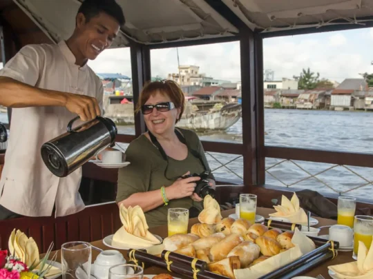 Crew serving breakfast to guests onboard Bassac Cruise on a luxury Mekong Delta cruise in Can Tho