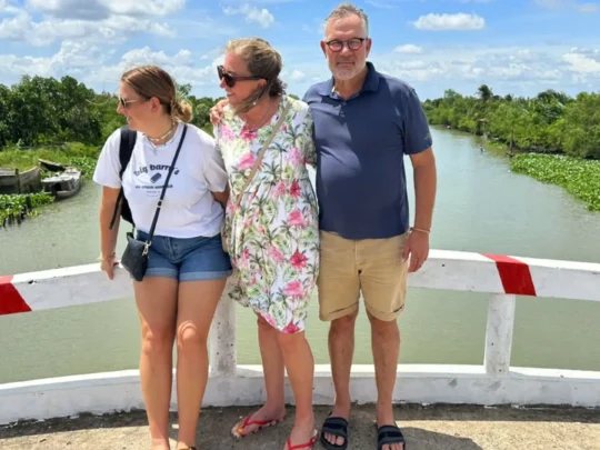 Tourists posing for a photo amidst the lush green foliage and fruit trees in Mekong Delta Tour Cai Be