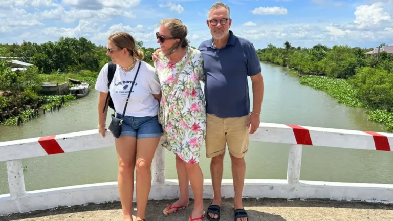 Tourists posing for a photo amidst the lush green foliage and fruit trees in Mekong Delta Tour Cai Be