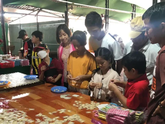 Children making or tasting coconut candy at a workshop table in Mekong Delta Tour Cai Be