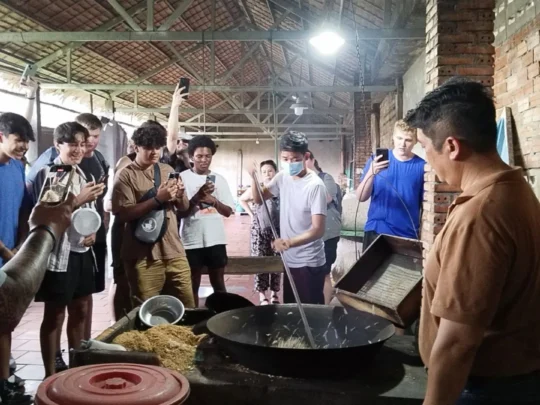 Guests watching and smiling at the making of puffed rice snacks in Mekong Delta Tour Cai Be