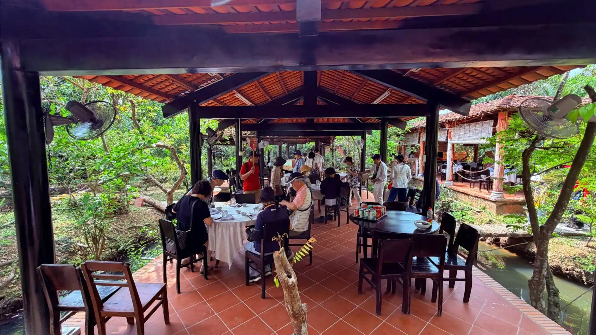An open-air garden restaurant area with tourists dining at Mr Kiet Ancient House