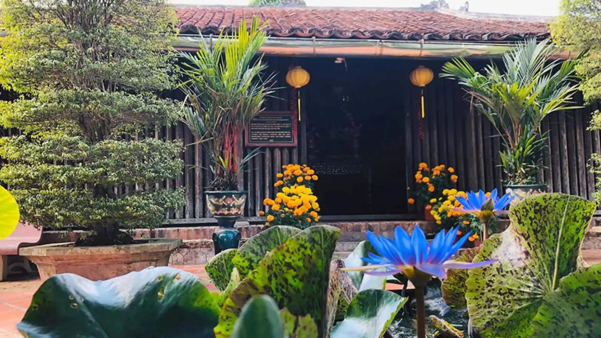 View of the wooden facade and garden at Mr Kiet Ancient House