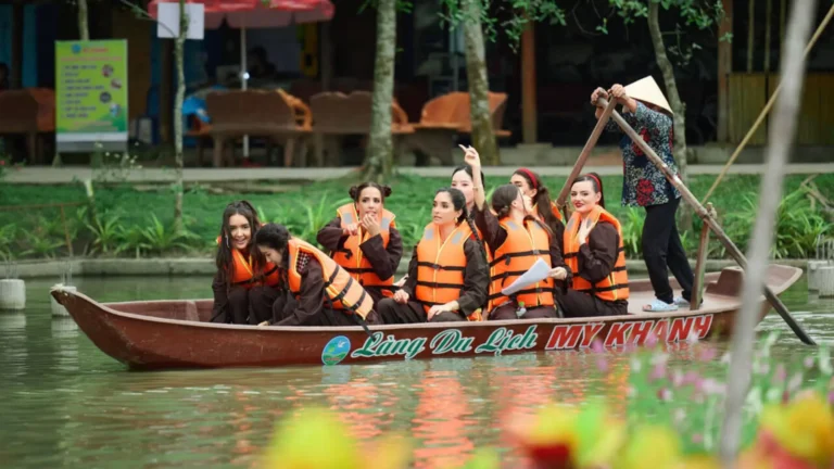Group of visitors enjoying a traditional boat ride at My Khanh Tourist Village