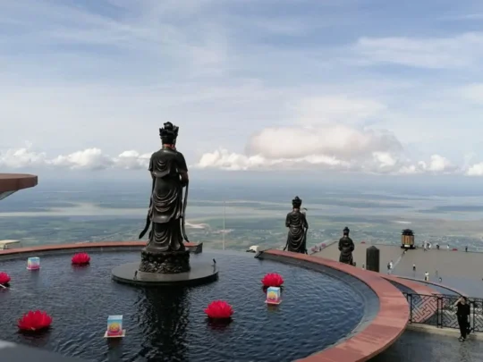 Buddha statue with prayer offerings on Ba Den Mountain summit, Tay Ninh