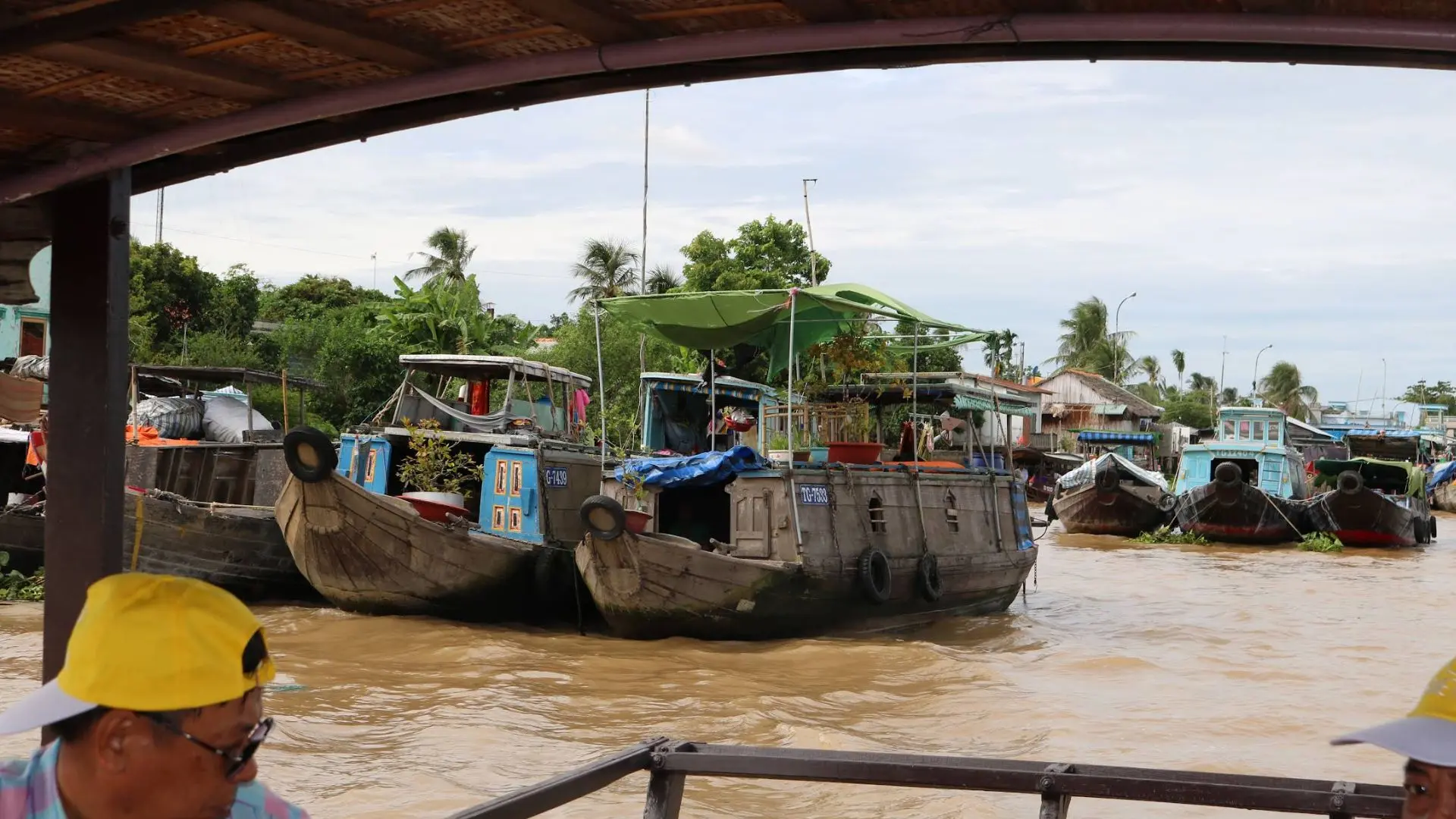 Several large wooden cargo boats docked along the riverbanks near Tan Phong Islet in the Mekong Delta