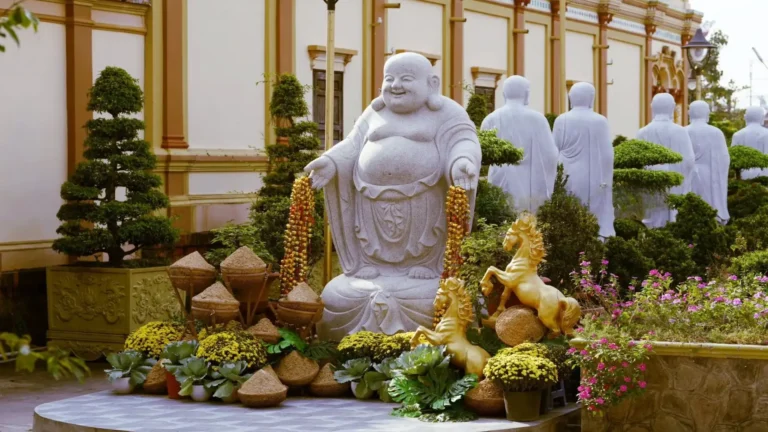 Laughing Buddha statue in the garden of Vinh Trang Pagoda, a famous temple in Tien Giang