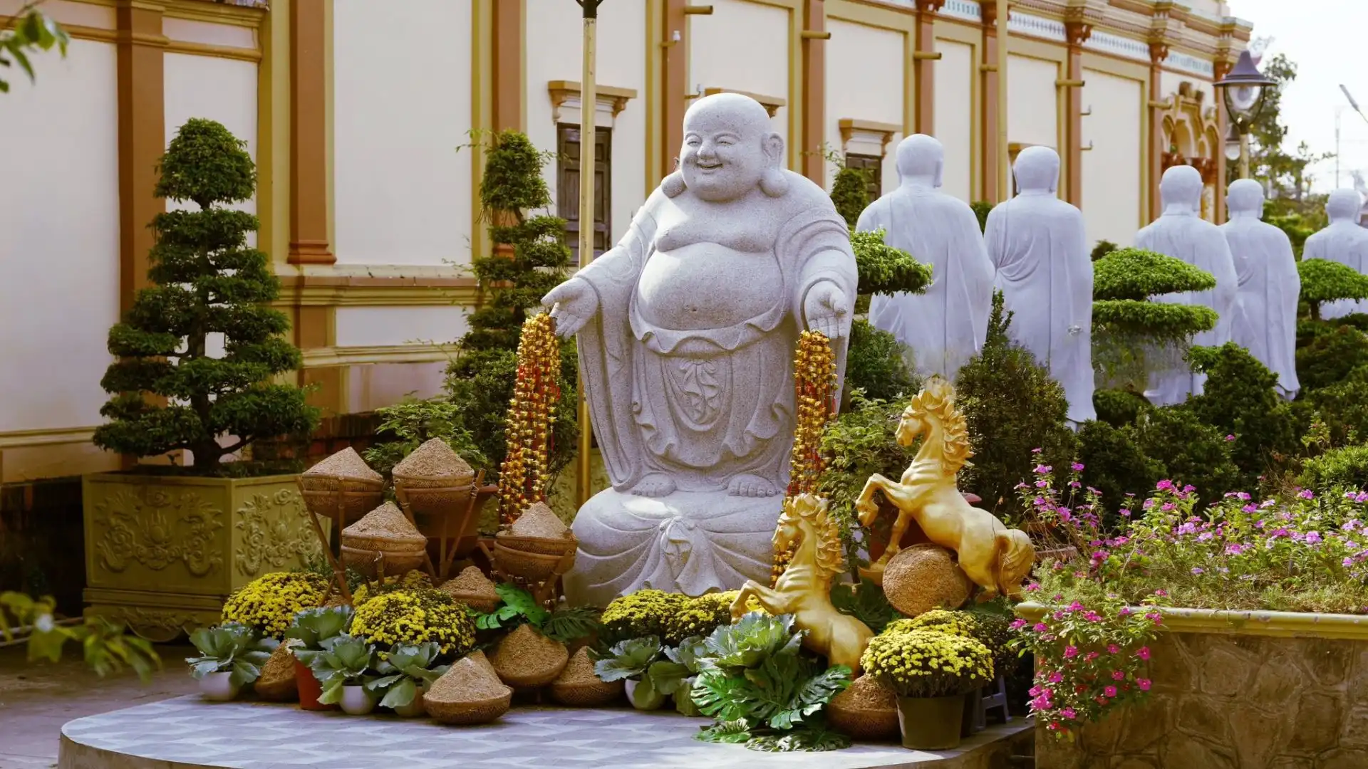 Laughing Buddha statue in the garden of Vinh Trang Pagoda, a famous temple in Tien Giang