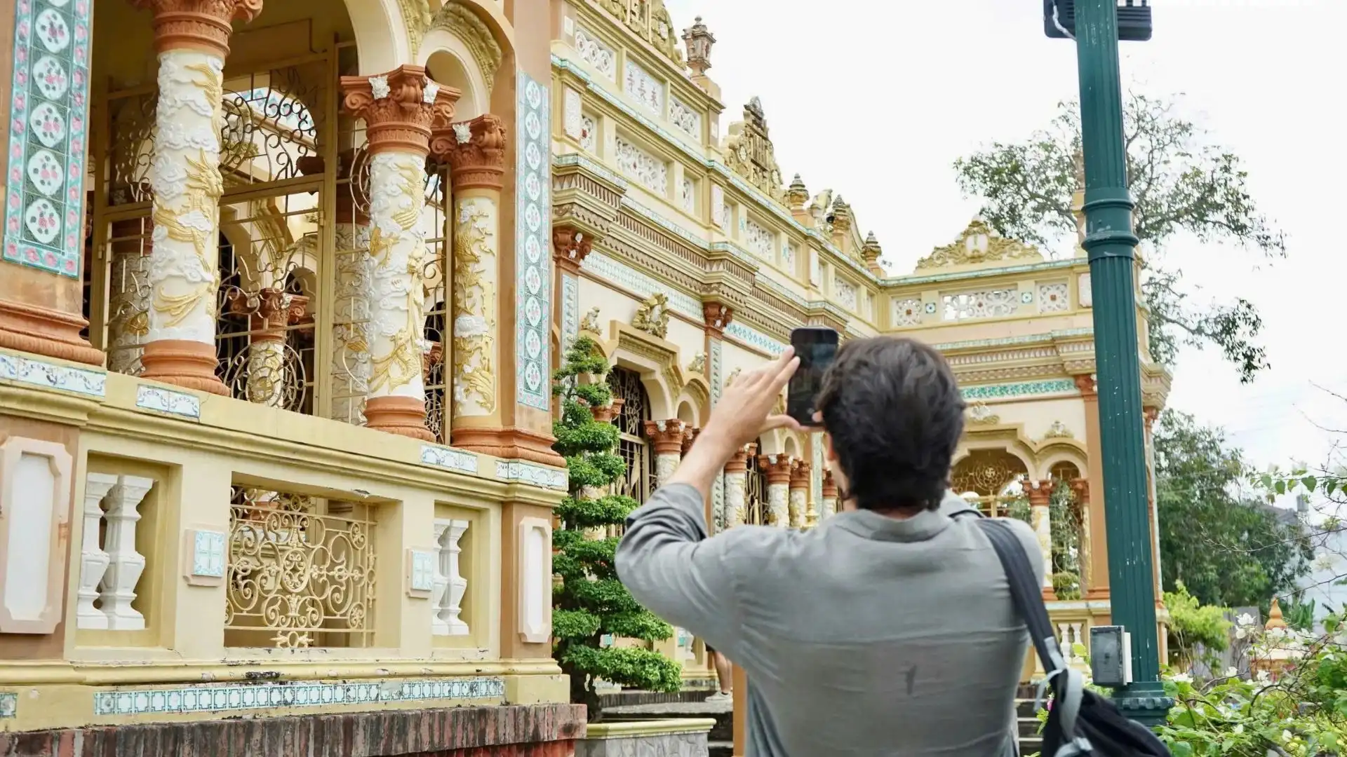 Visitor viewing the ornate architecture of Vinh Trang Pagoda in My Tho, Tien Giang
