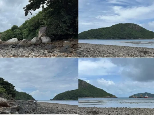 Panoramic view of Ong Cau Beach in Con Dao with rocky shore, calm ocean, and surrounding green mountains