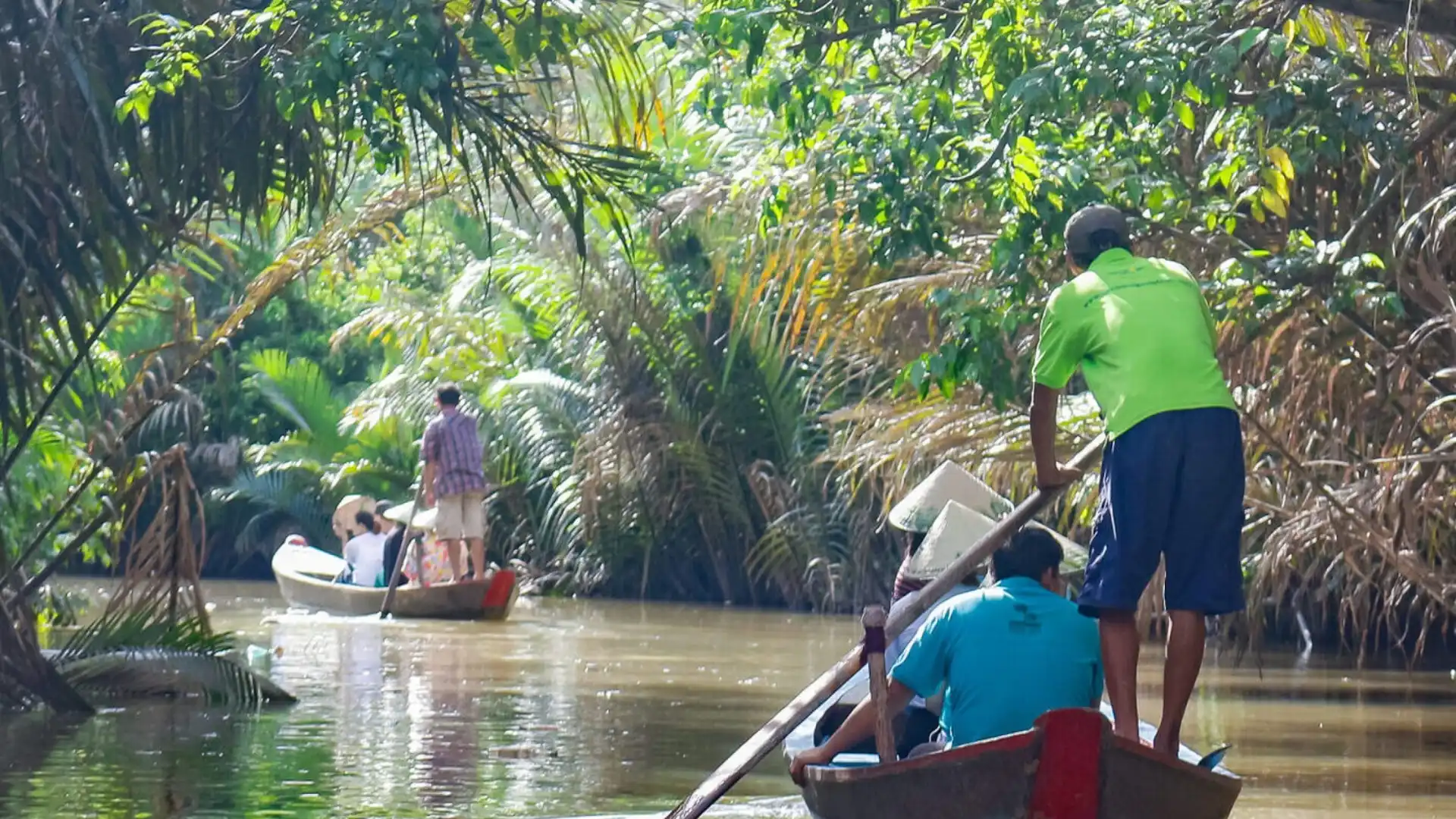 Rowing sampan through a coconut-lined canal during the Ben Tre tour