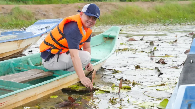 Sampan boat rowing through water lily swamp in Chau Doc