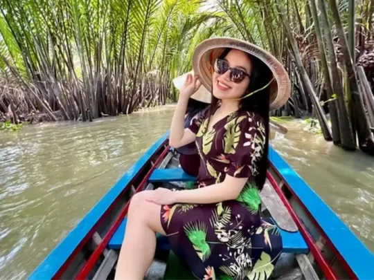 Tourist enjoying peaceful sampan ride along shaded canal in Mekong Delta