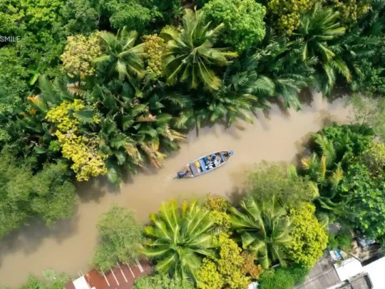 Wooden boat cruising through a small green canal in Can Tho
