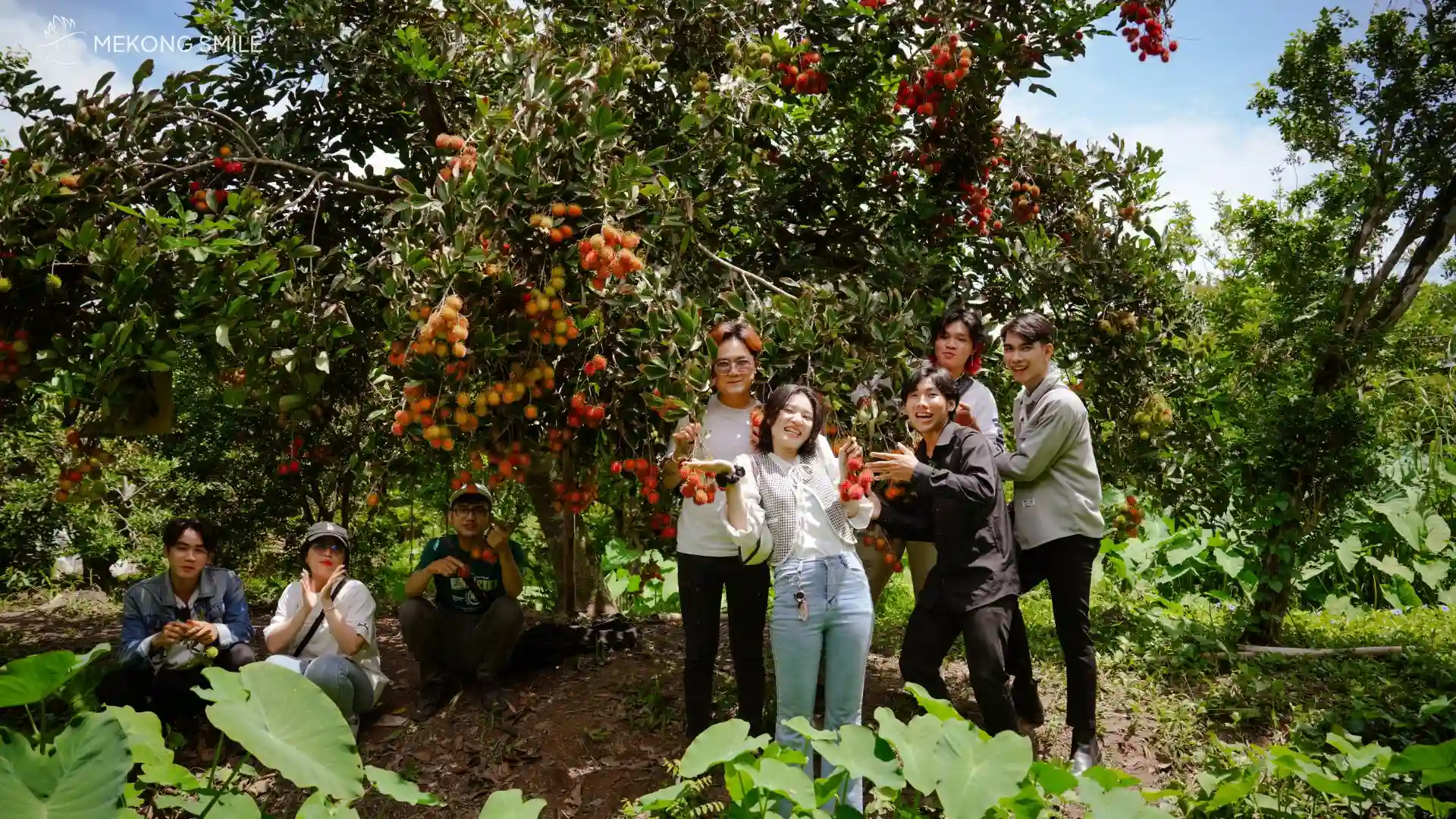 A group of tourists showing their excitement while visiting a lush, fruit-filled garden on Son Islet.