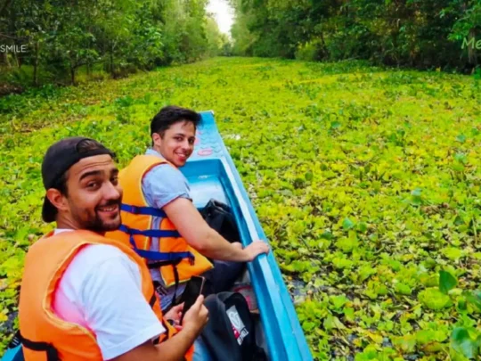 A tourist showing excitement as they ride a sampan through canals covered in lush green duckweed