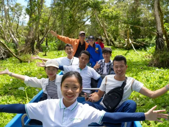 Travelers on a traditional sampan, gracefully moving through the serene Tra Su forest